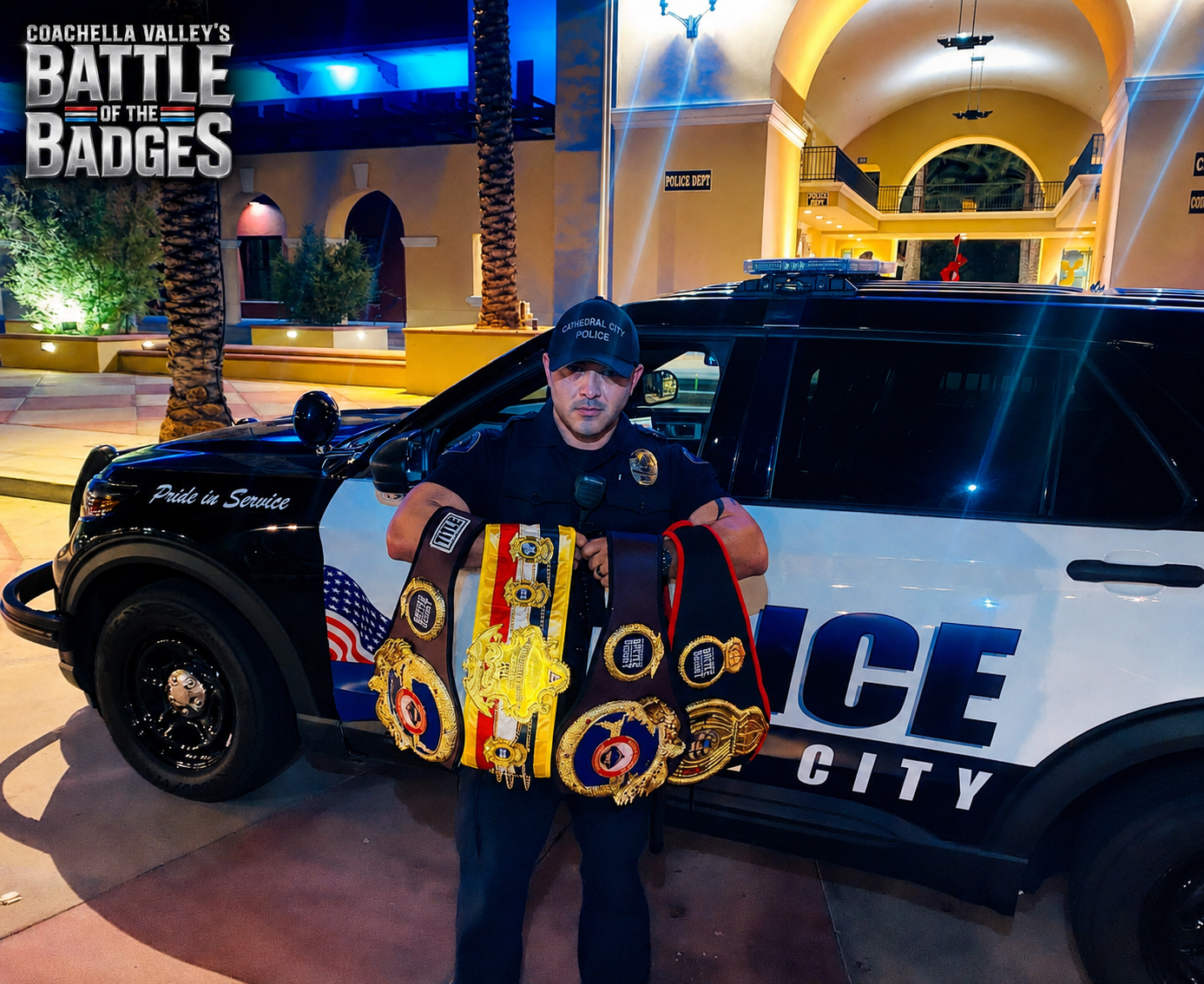 Cathedral City police officer holding championship belts in front of a patrol vehicle